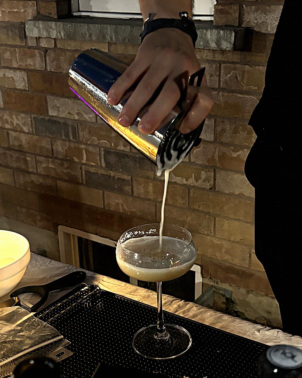 A cocktail being strained from the shaker into a chilled coupe